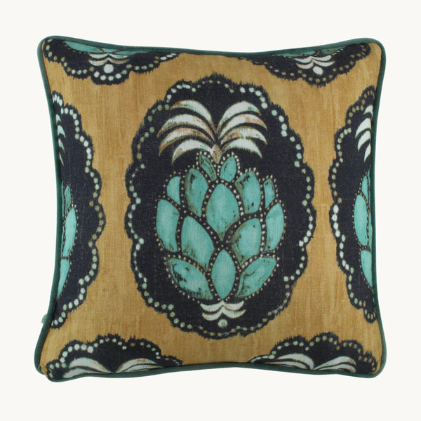 photo of a cushion with a large stylised turquoise pineapple on a black cameo with a gold basecloth. 