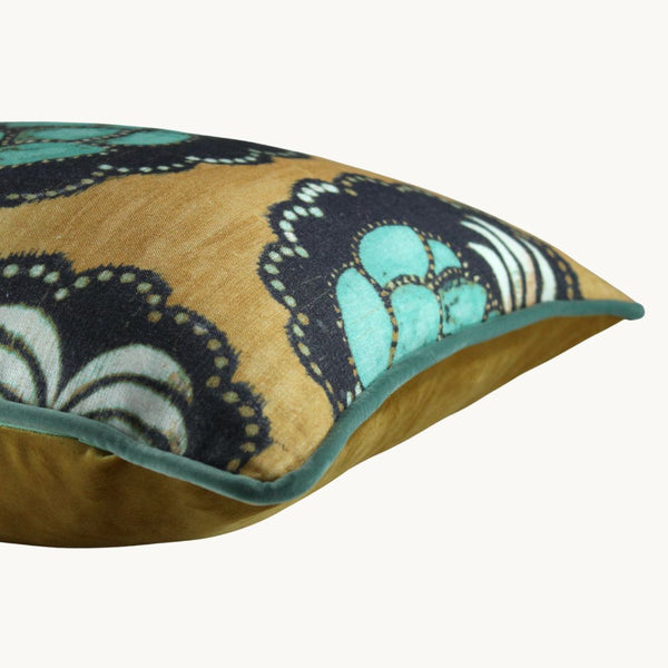 Side photo of a cushion with a large stylised turquoise pineapple on a black cameo with a gold linen basecloth.
