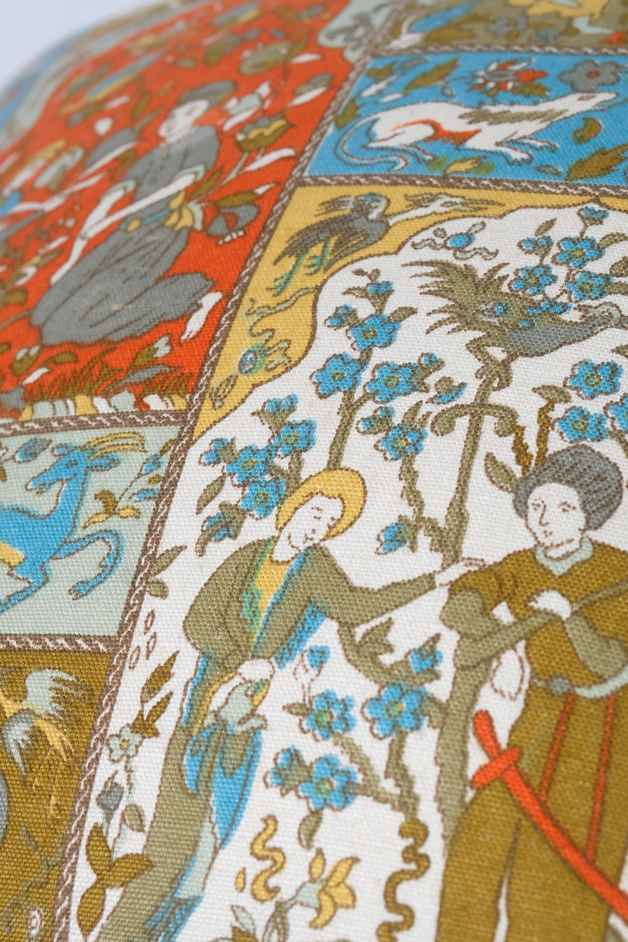 Close-up of a detailed fabric pattern with medieval-style figures and animals.