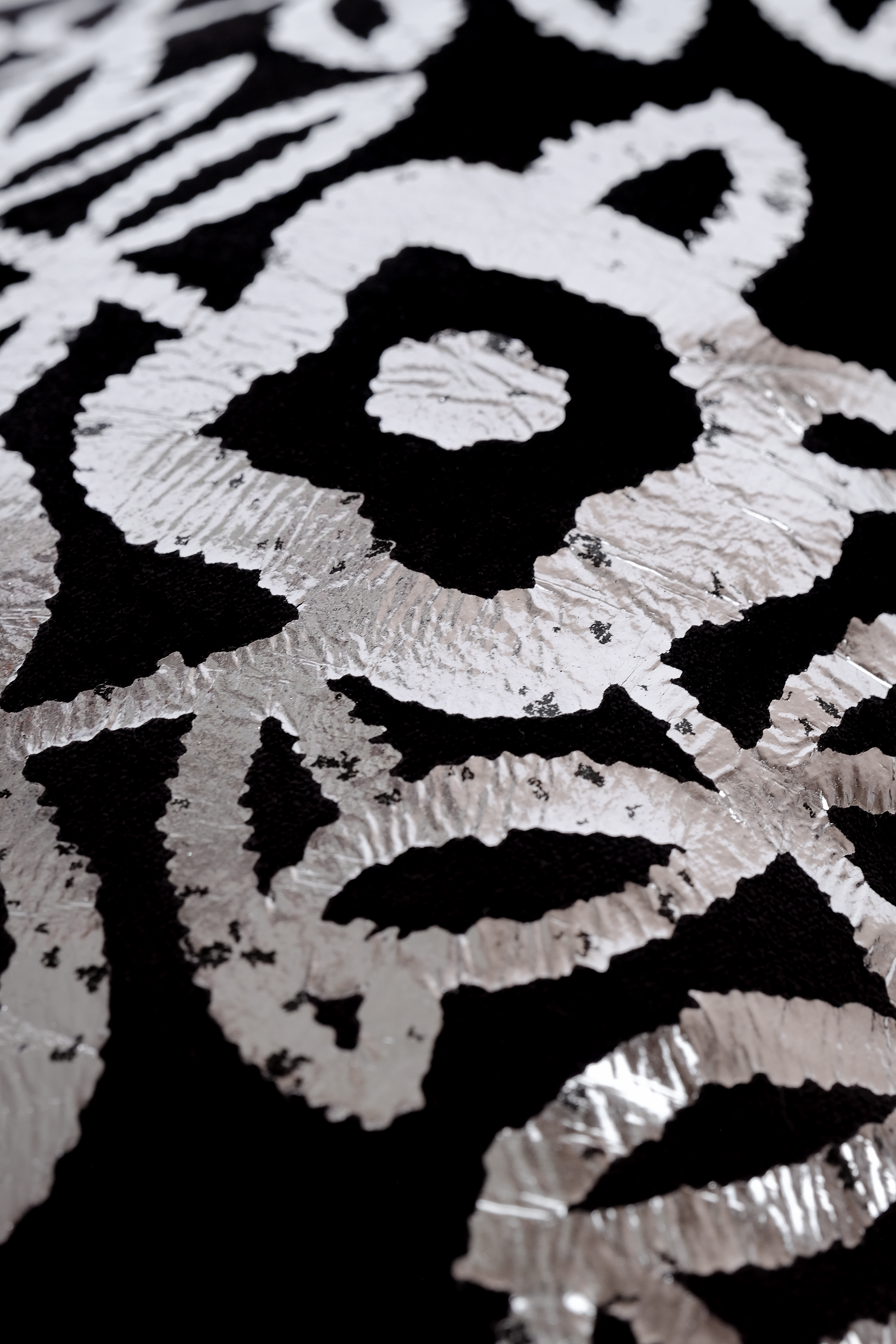 Close up  of a black velvet textile with a shiny metallic silver foil floral pattern