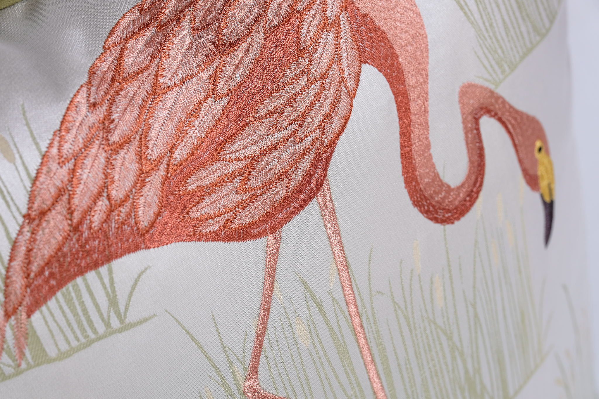 Close-up of a pink flamingo illustration on a light background with pale green grass and a yellow beak accent.