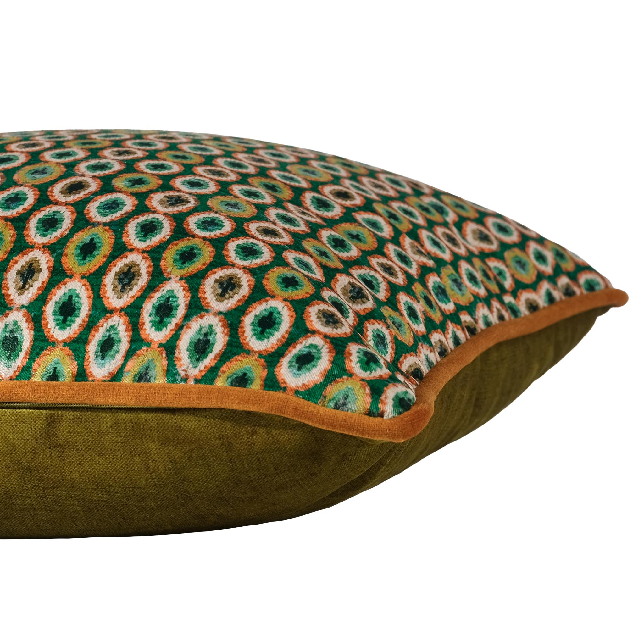 A close-up of a decorative throw pillow featuring a green and orange geometric patterned top half and an olive green velvet bottom half, finished with a rust-orange piped edge.