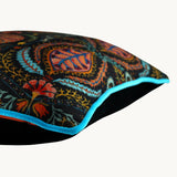 Side photo of a black based cushion with very detailed colourful paisley-esque designs inspired by the Woodstock Era.