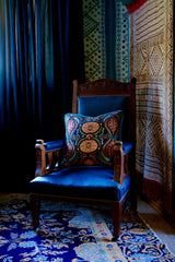 Maximalist corner of a room with brightly coloured cushion on a vintage wooden chair