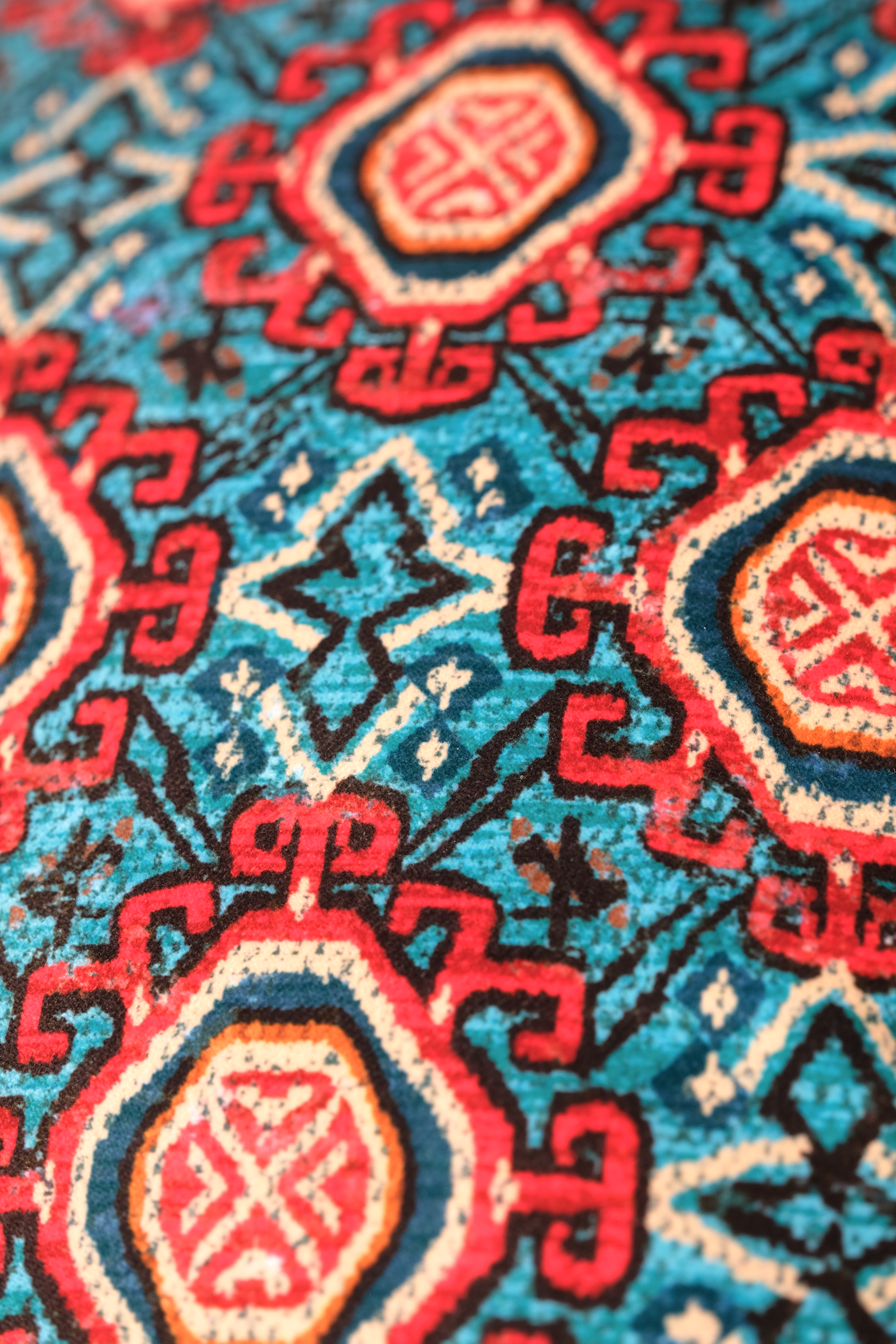 Close-up of a colorful patterned velvet with red and aqua colors.