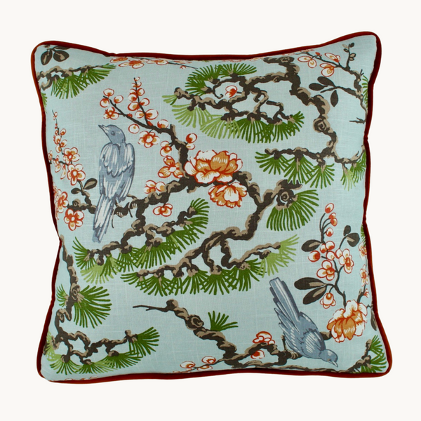 Photo of a cushion with an oriental inspired design featuring birds, blossoms and evergreen coniferous trees
