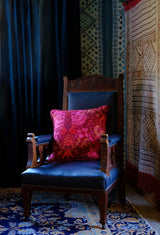 Maximalist room setting with a vintage wooden chair with a bright red and pink damask cushion 