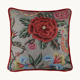 Photo of a floral linen cushion - grey background, red, dusty pink and blue stylised flowers with red velvet piping