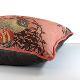 Side view of a floral cushion with a salmon coloured linen background and red, blush pink, and muted turquoise flowers.
