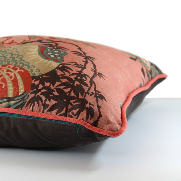 Side view of a floral cushion with a salmon coloured linen background and red, blush pink, and muted turquoise flowers.
