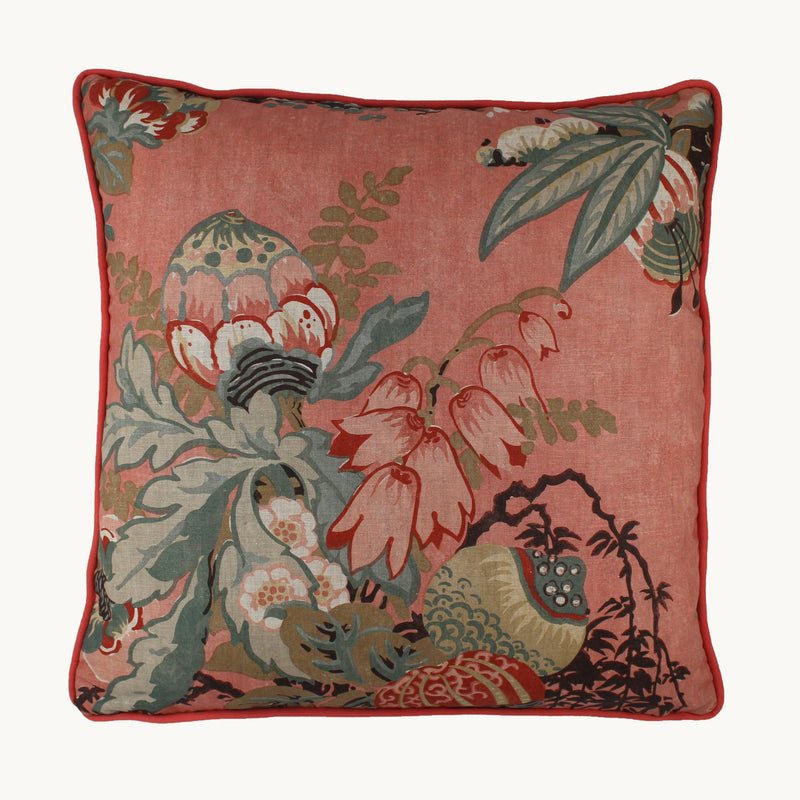 Photo of a floral cushion with a salmon coloured linen background and red, blush pink, and muted turquoise flowers.