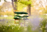 Photo of three green patterned cushions stacked on a Bentwood chair in a woodland setting