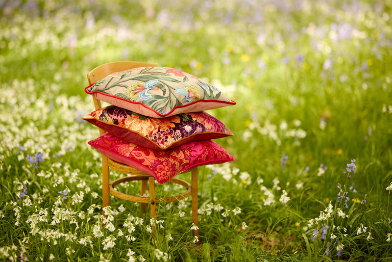 Image of three floral cushions stacked on a Bentwood chair in a woodland setting