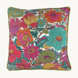 Photo of a bright colourful floral cushion with retro inspired flowers in hot pink, grape, bright turquoise, coral and orange with caper green piping 