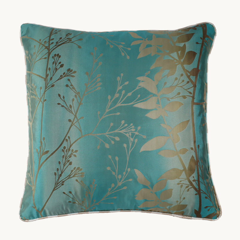 Photo of a silk blend cushion in a luminous aqua ombre with sand coloured leaves with striped piping