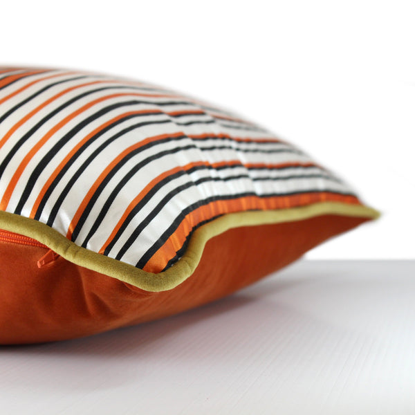 Side view of a cushion with an orange, white, green and black barcode like stripe
