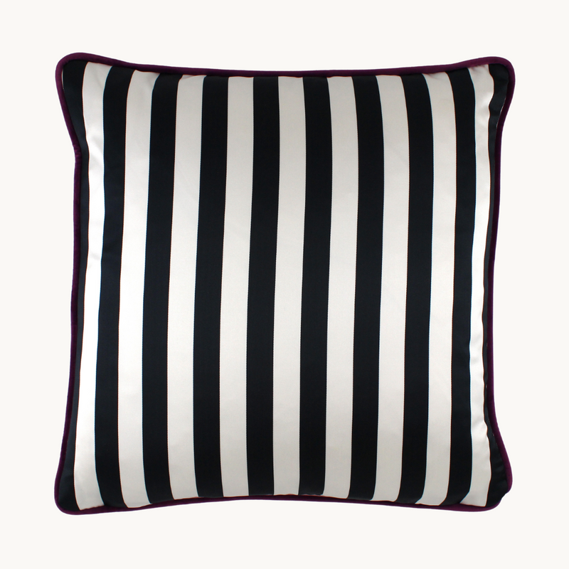 Crisp black and white striped back of a vibrant floral cushion with a combination of painterly and digital blooms in purple, raspberry, lime, black and white.