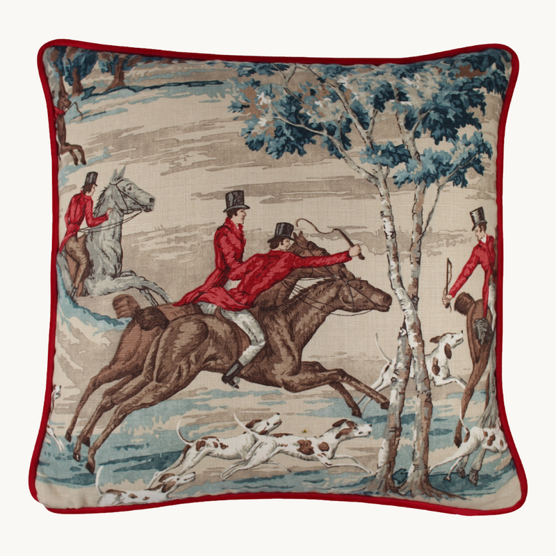 Photo of a linen cushion with a classic English hunting scene of horses and riders and hounds in blue, red, brown and taupe