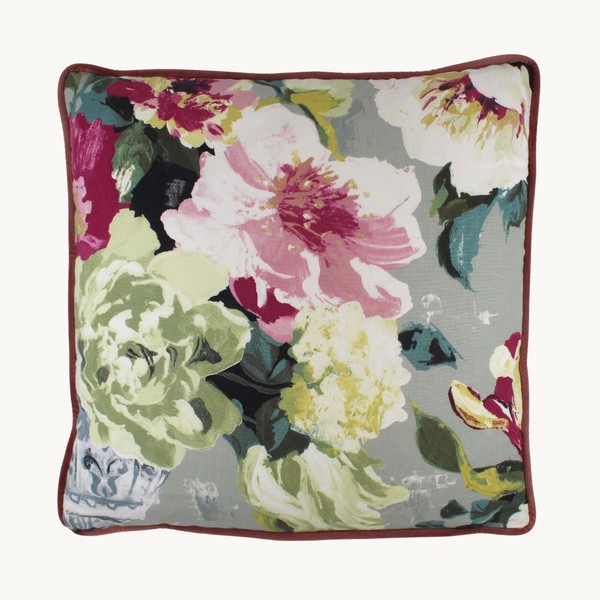 Photo of a cushion in a floral with a light grey background and large scale blooms in pink, magenta and very pale green