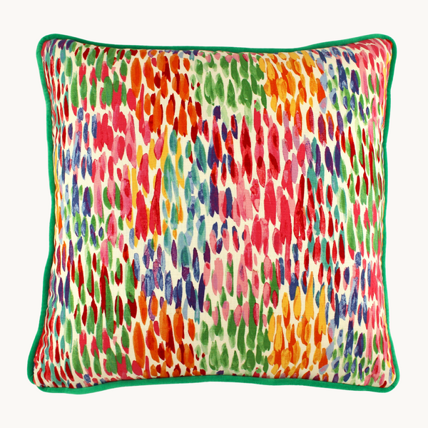 Photo of a square cushion with a rainbow of coloured dashes and emerald green piping.