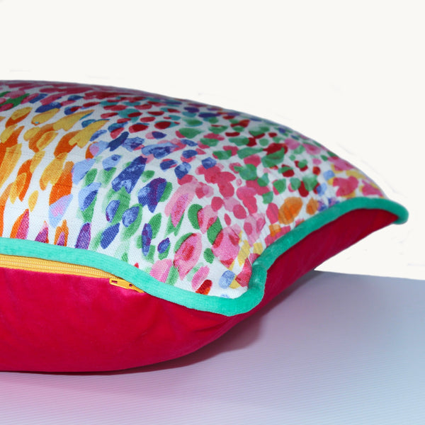 Photo of the side view of a cushion with a rainbow of coloured dashes and emerald green piping.