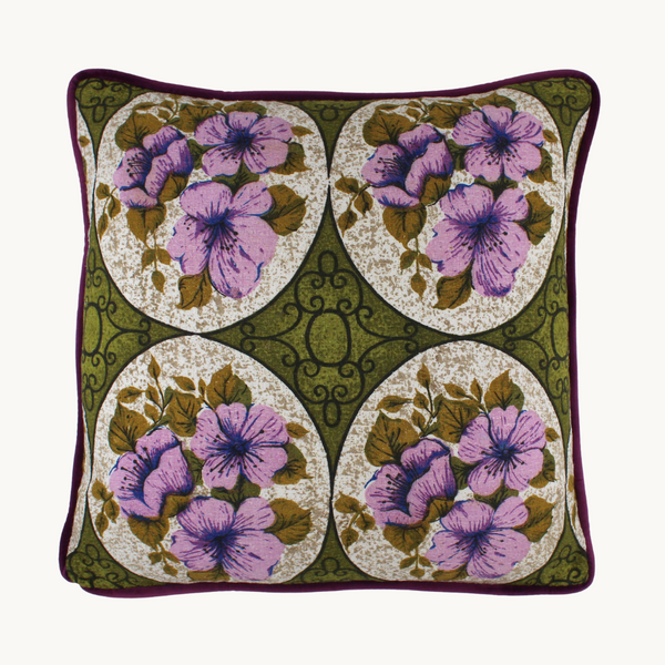 Photo of a cushion made from a vintage barkcloth in a sweet floral design with medallions of lilac flowers and an olive green background