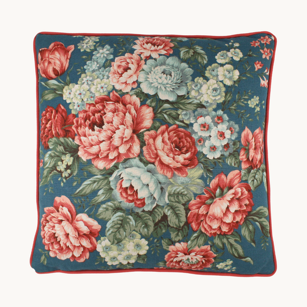 Photo of a cushion made from a vintage linen with a large boquet of flowers in coral, denim blue, powder blue and sage green