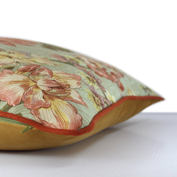 Side view of a cushion made from a vintage linen in a floral design with a sage green background and dahlias in pinks and soft rust with hints of lilac with a rust linen piping and gold velvet back