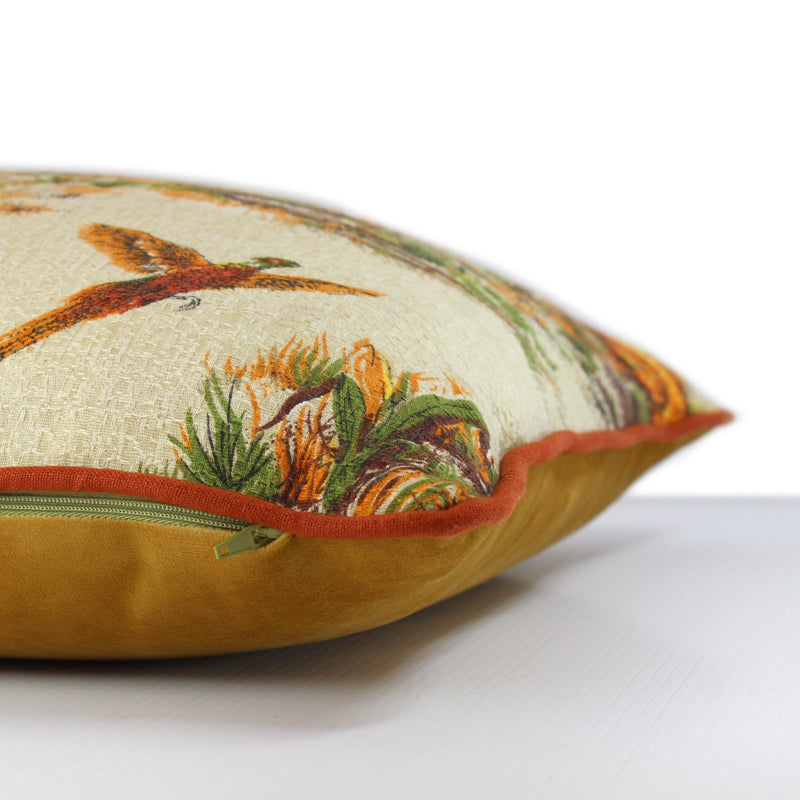 Side view of a cushion in a vintage barkcloth showing setter dogs and pheasants in an autumn colour palette with rust linen piping and a gold velvet back