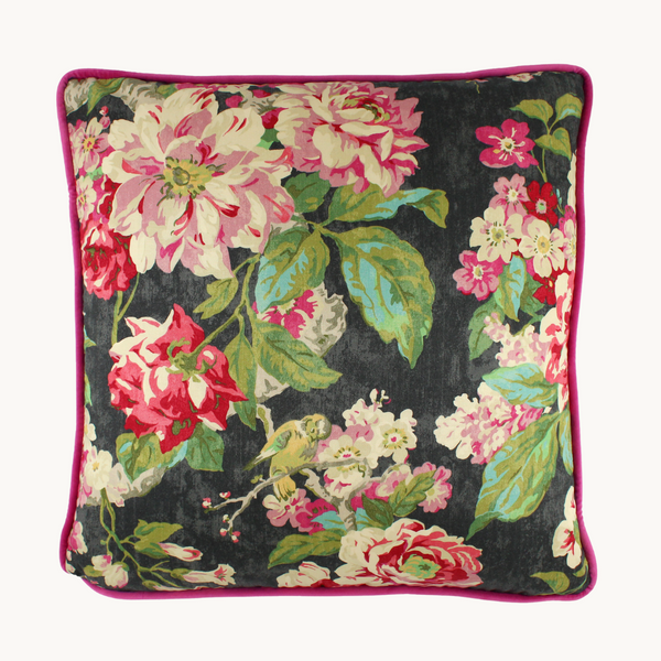 Photo of a cushion in a bright floral design with a charcoal base and bright pink, green and aqua roses and leaves
