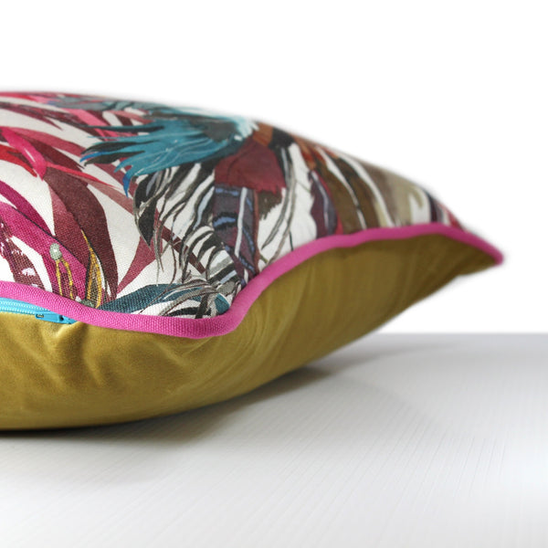 Side view of a cushion made from a printed linen with colourful native american indian feather headdresses, fuschia cotton piping and a chartreuse velvet back